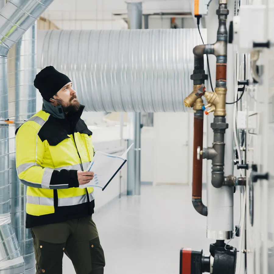 Talotekniikka-ammattilainen tarkastaa ilmanvaihtojärjestelmää - Tammi Kiinteistötekniikka.