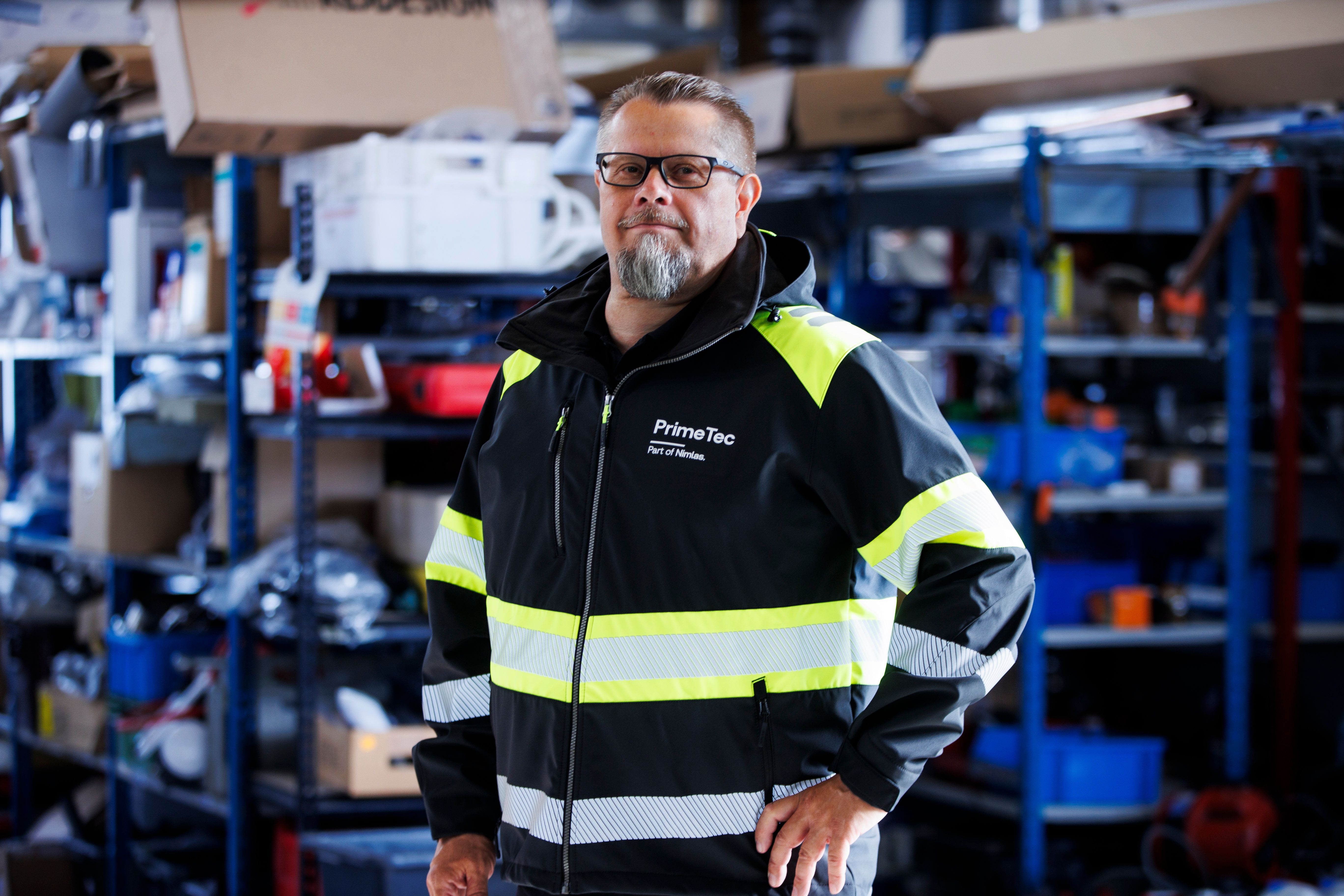 Markus Hämäläinen, PrimeTecin toimitusjohtaja seisoo yrityksen varastossa. Hänellä on päällään takki, jossa on teksti PrimeTec Part of Nimlas.