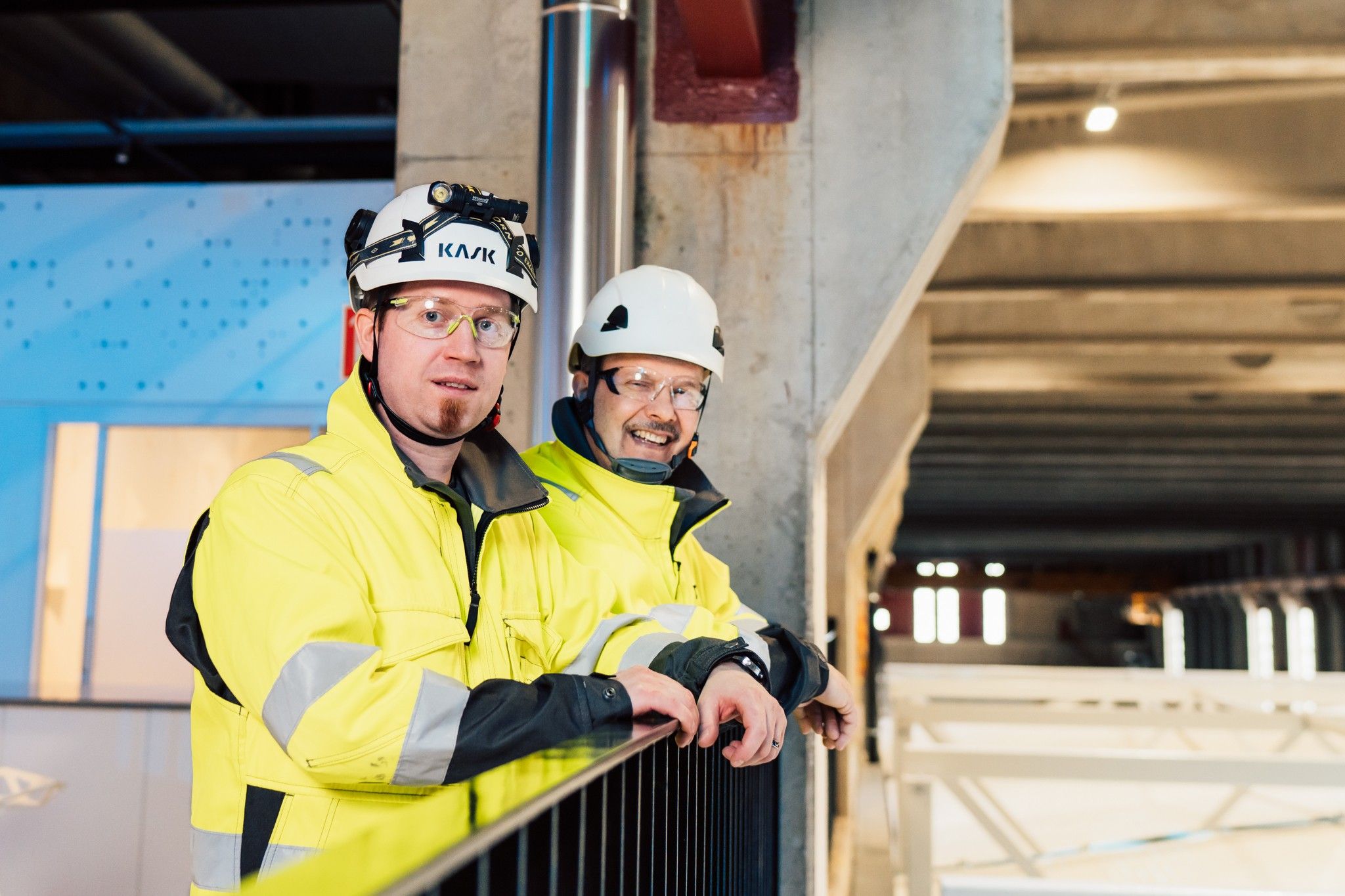 Kaksi Paikallis-Sähkön työntekijää keltaisissa huomiovaatteissa ja suojakypärissä datakeskushankkeella.
